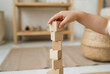 © Sachin - Child stacking wooden blocks to build a tower for fine motor skills development in a minimalist Montessori playroom