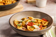 © Stacy Howell - Tortellini in a pottery bowl with sauce, tomatoes and basil sprinkled with cheese on a stone surface
