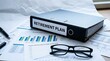 © Mostafizur - A professional workspace featuring a binder labeled Retirement Plan surrounded by financial charts a pair of glasses and a pen ideal for business finance and retirement planning content.