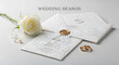 © Indh - Elegant white wedding invitation suite with laser-cut details and gold rings, accompanied by a single white rose, symbolizing love and commitment