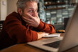 © Davor - Middle-aged man stressed while working on laptop in home kitchen