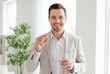 © Meow Creations - Smiling handsome man holding a vitamin pill and a glass of water for his health