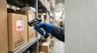 © WisChi - Hand in blue glove scanning barcode on cardboard box in warehouse aisle with stacked inventory