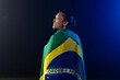 © Wavebreak Media - Woman standing wrapped in Brazilian flag showing ORDEM E PROGRESSO, studio blue rim light, grass