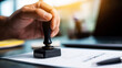 © Bonsales - Hand stamping official document, authorizing agreement, certifying business paperwork with legal approval on desk