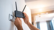© Bonsales - Hands connecting a wifi router, installing high speed internet in a contemporary home. Setting up wireless network access
