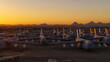 © AmazingAerialAgency - Tucson, United States - 06 February 2025: Aerial view of colossal aircraft gleaming under a fiery desert sunset, silhouetted against rugged mountains.