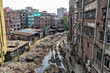 © AmazingAerialAgency - Keraniganj, Bangladesh - 11 April 2026: Aerial view of a grim ribbon of refuse and mud carving its path between densely packed, weathered residential buildings under a muted sky.