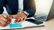 © peopleimages.com - Sticky note, notebook and hands of businessman in office writing information for finance report. Cellphone, laptop and male financial manager with research for online investment proposal in workplace