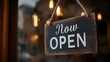 © saran - A wooden sign saying Now Open hangs on a rope in front of a window