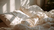 © Sevinj - A corner of a messy but aesthetic bed with crumpled white linen sheets and ivory cotton duvet, soft warm sunlight streaming through a window, airy and bright, neutral tones