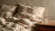 © Sevinj - An unmade bed with light beige linen bedding, a simple wooden bedside table with a glass of water, soft morning haze lighting, monochromatic cream aesthetic