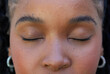 © Wavebreak Media - African adult woman in studio closing eyes wearing neutral makeup textured skin silver hoops braids
