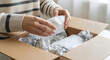 © FantasticPixel - Person unpacking fragile item from cardboard box with bubble wrap in natural indoor lighting for shipping and delivery