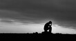 © Mike - Silhouette of a person sitting alone in despair against a dramatic sky.
