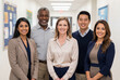 © Meow Creations - Diverse team of smiling teachers and school administrators standing in hallway