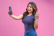 © ChristyMerry - Smiling young Asian girl wearing blue shirt holding a smartphone and doing video call pose.