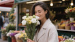 © Lumi Stock Studio - Smiling Woman Smelling White Rose Bouquet at Outdoor Flower Market, Happy Female Customer Buying Fresh Flowers