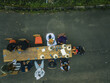 © Amazing Aerial - Aerial view of a long wooden table set for a communal meal, surrounded by people gathered on chairs, contrasting sharply with the dark asphalt road, Obudu, Cross River, Nigeria.