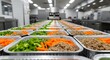 © Albaloshi - sealed aluminum trays of cooked meals.Food factory conveyor belt modern food processing plant where a continuous line of pre-packaged meals, containing diced carrots,