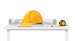 © pookie - A vibrant yellow safety hard hat rests on detailed architectural blueprints alongside a retractable tape measure and a sharpened pencil on a white desk.