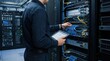 © Oleg - Professional network technician configuring server rack in data center. Data center infrastructure for network maintenance and digital connectivity.