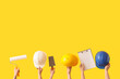 © Pixel-Shot - Male hands with painter's tools, hardhats and clipboard on yellow background