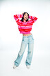 © deagreez - Happy young woman in pink striped sweater and wide‑leg jeans smiling and posing in casual fashion portrait