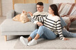 © Pixel-Shot - Beautiful young couple with cute Maine Coon cat in living room