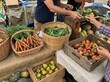 © Iryna - Hands of customer and vendor with an authentic and community-focused mood exchanging money for fresh organic vegetables and fruits representing local farmers market and sustainable shopping on rustic