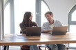 © luciano - Young Couple Working Together on Laptops in Bright Home Office During Casual Business Discussion