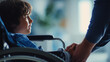 © KotBaton - Child in wheelchair holding adult hand. Support, care, trust and inclusive healthcare concept.