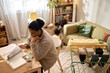 © Seventyfour - Wide angle view of African American mother reviewing household bills while caring for children at home, showing financial hardship. Ideal for poverty, budgeting, debt, welfare campaigns