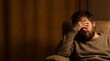 © Emberspirit - Depressed man sitting on a chair covering his face in a dark room