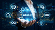© sohel - Hand holding agile globe with digital transformation icons in futuristic business setting
