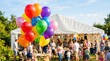 © mashimara - Colorful balloons float at a lively outdoor summer party with a large tent