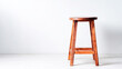 © Bonsales - Wooden stool standing on white floor against a clean minimalist background with ample copy space