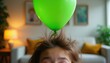 © Pete - Green balloon floats above person hair standing up from static electricity. Kid learns physics fun science experiment at home. Playful education, indoor activity.