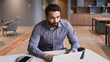 © insta_photos - Serious indian businessman remotely working at home watching online learning training webinar for employees. Latin Hispanic student having online virtual video call on computer in creative office.