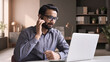 © insta_photos - Indian business man professional employee, remote consultant, customer service support manager wearing headset talking at virtual meeting consulting client on video call at home office call center.