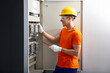 © New Africa - Electrician with screwdriver checking electrical meter indoors
