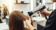 © jendralbiribiri - Professional hairdresser's hands expertly dry a client's beautiful long brown hair with a modern blow dryer in a bright, inviting beauty salon, creating a perfect fresh style for a polished look.