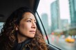 © sogap - Young woman contemplating city view during rainy commute in taxi or rideshare