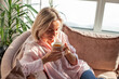 © Tatyana Gladskih - Adult smiling Woman drinking coffee on sofa at sunlight living room, relax, rest and wellbeing.