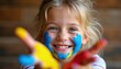 © Vadym - Happy girl with face and hands painted in bright blue yellow and red colors. Child enjoys finger painting activity, expresses pure joy and creativity. Small artist is having fun.