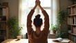 © Vadym - Woman in cozy sweater does overhead arm stretch at desk in sunlit room. Peaceful home office break, stretching upward, feeling refreshed and balanced. Mindful moment.