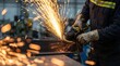© CuteBee - Industrial metal fabrication worker using angle grinder to cut steel beam creating bright orange sparks in workshop environment with focus on heavy machinery and manual labor expertise
