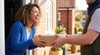 © ibhonk - Smiling woman accepting brown cardboard package from delivery courier outside residential brick house.