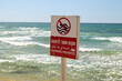 © Vladimir Bikhovskiy - A close up shot of a red and white swimming prohibited warning sign at a beach in Israel, indicating that entering the rough sea is currently dangerous for visitors due to strong waves and wind