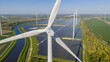© AmazingAerialAgency - Aerial view of Zonnepark Eekerpolder featuring wind turbines and vast solar panel arrays next to a canal in Scheemda, Groningen, Netherlands.